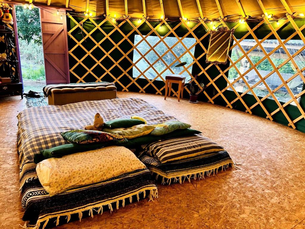 a bed in a room with blankets and pillows at A Magical Cosy Garden Yurt in Ladyʼs Odell