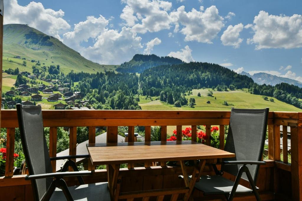 una mesa de madera y sillas en un balcón con vistas en Chalet Anou - proche pistes de ski, en Le Chinaillon