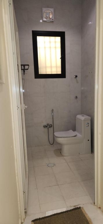 a bathroom with a toilet and a window at منتجعات رغيد الفندقية الزهرة in Hail