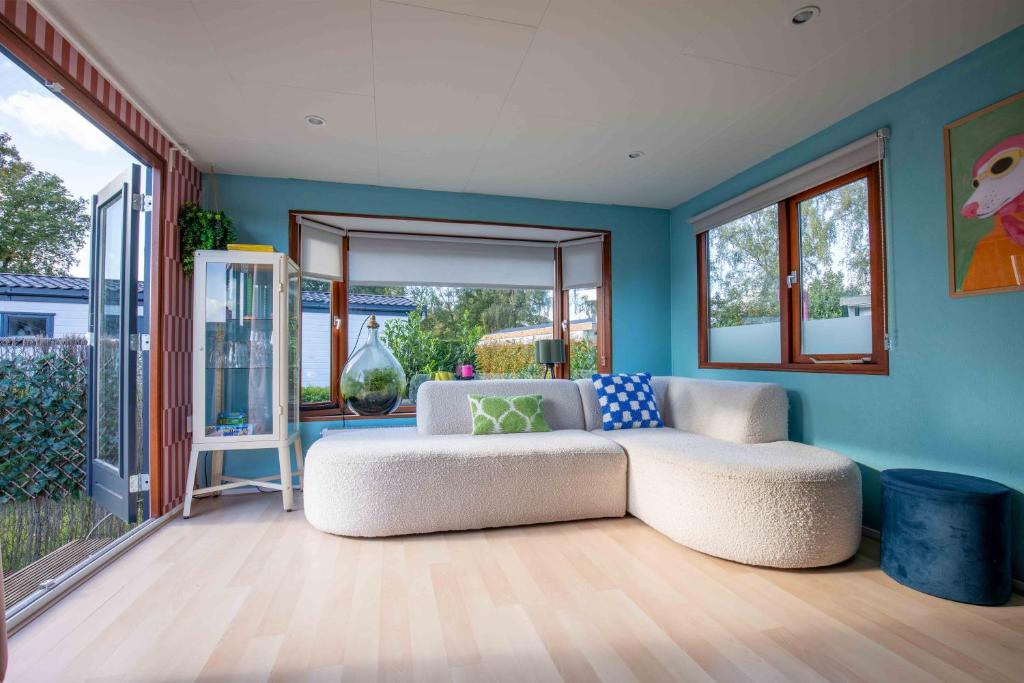 a living room with a white couch and blue walls at Tiny Cabin Sole op de Veluwe in Putten