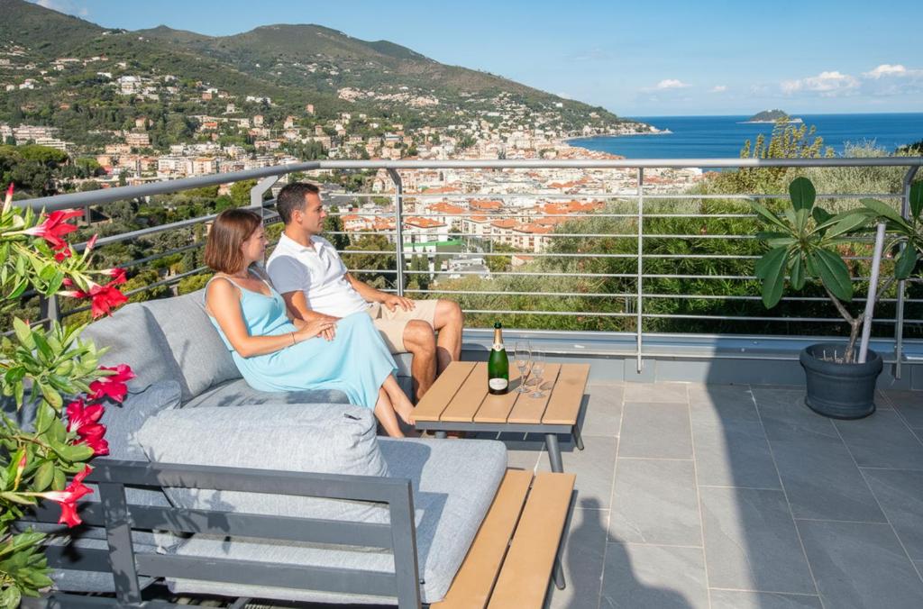 un uomo e una donna seduti su un divano su un balcone di Luce Di Mare ad Alassio