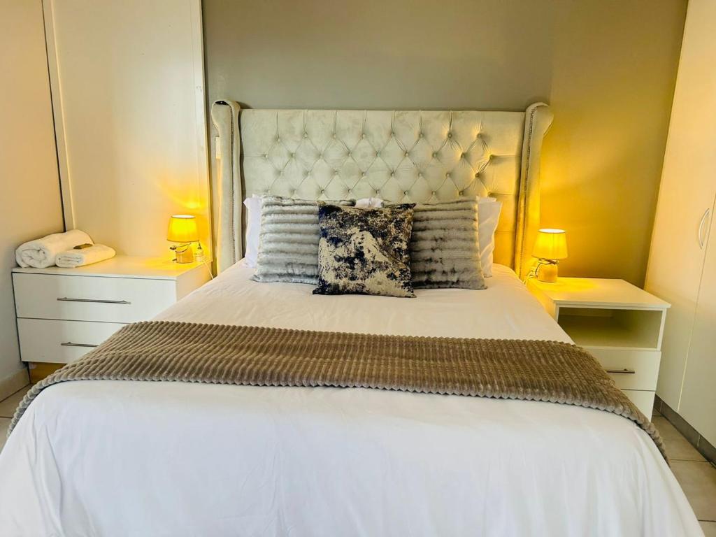 a bedroom with a large white bed with two lamps at Richards Bay Serenity Retreat Apartments in Richards Bay