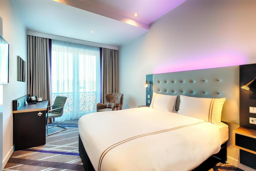 Una habitación de hotel con una cama grande y un escritorio. en Premier Inn Lübeck City Stadtgraben, en Lübeck