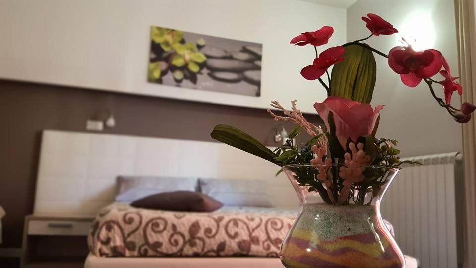 un vaso con fiori rossi su un tavolo con un letto di B&B Villa Letizia Inn a Castelbuono