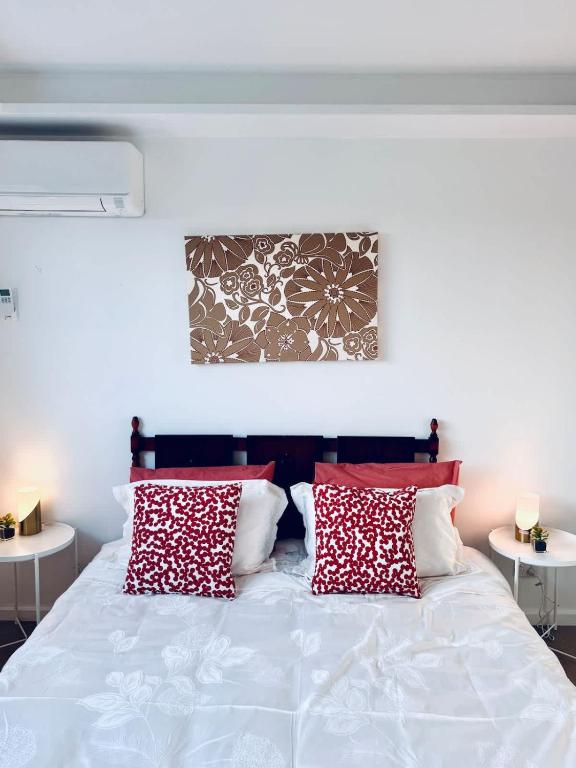 MetaWise Cozy Retreat close to Monash Uni and Chadstone U3 في Oakleigh South: غرفة نوم بها سرير مع وسائد حمراء وبيضاء