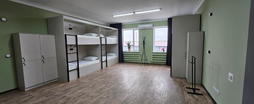 a large room with bunk beds and a room with a window at Koktem hostel in Aktobe