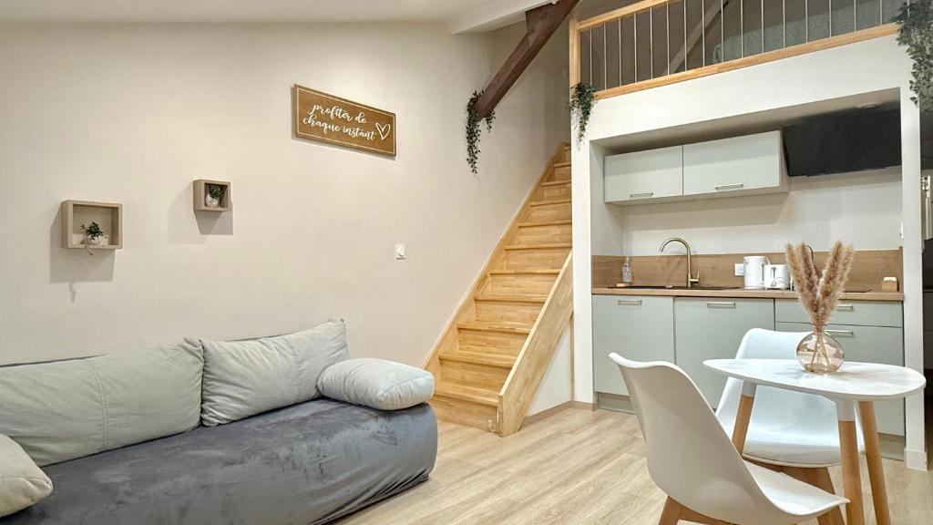 ein Wohnzimmer mit Couch und Tisch und eine Küche in der Unterkunft Le cocon mâconnais pour deux in Mâcon