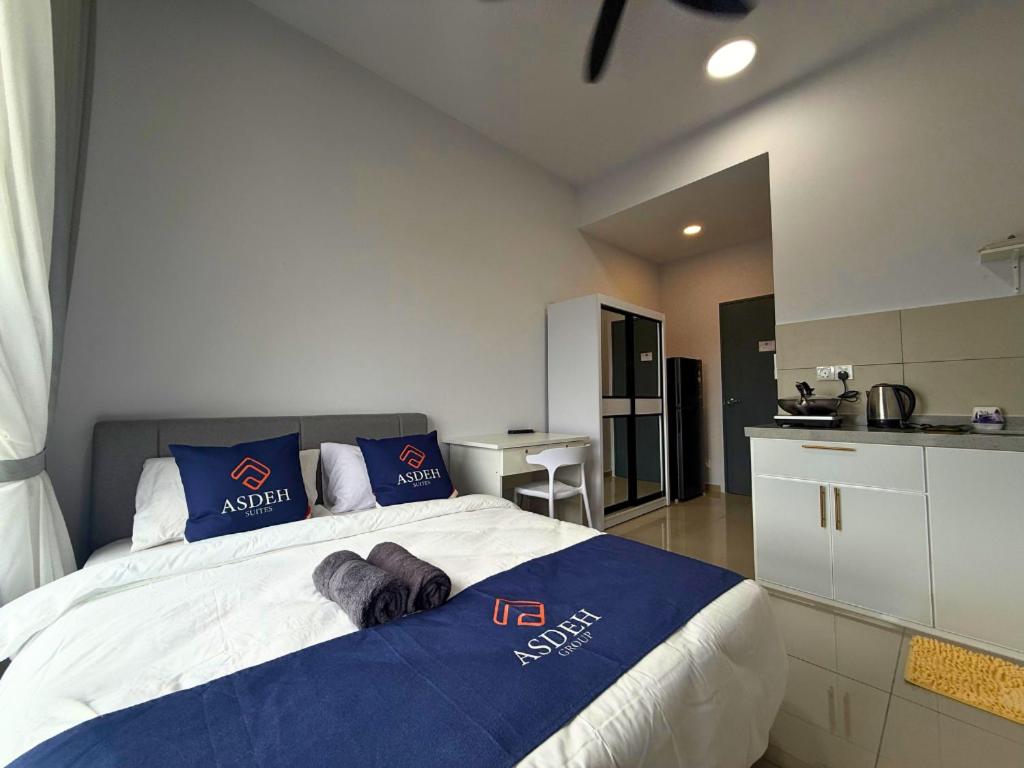 a bedroom with a large bed and a kitchen at Midlands City Broga Semenyih by ASDEH Suites in Semenyih