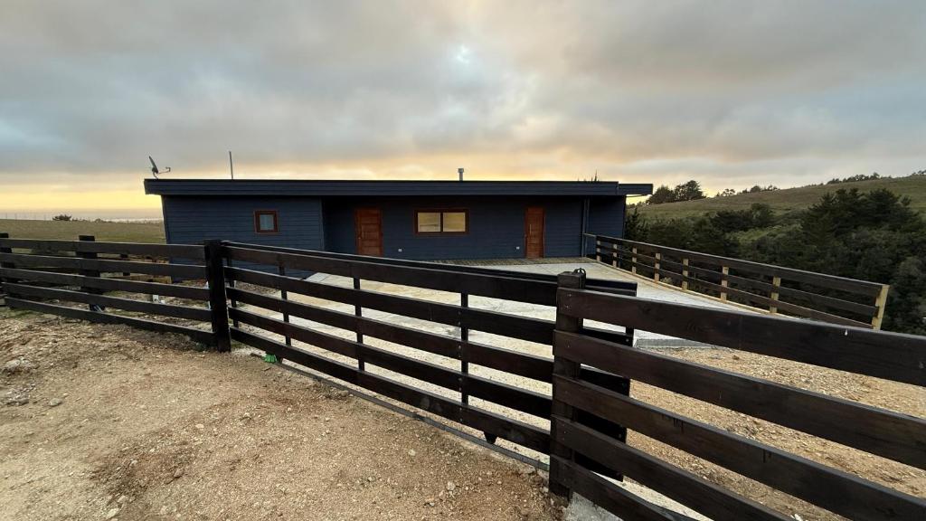 a blue house with a fence in front of it at Casa La Laguna - Pichilemu in Pichilemu