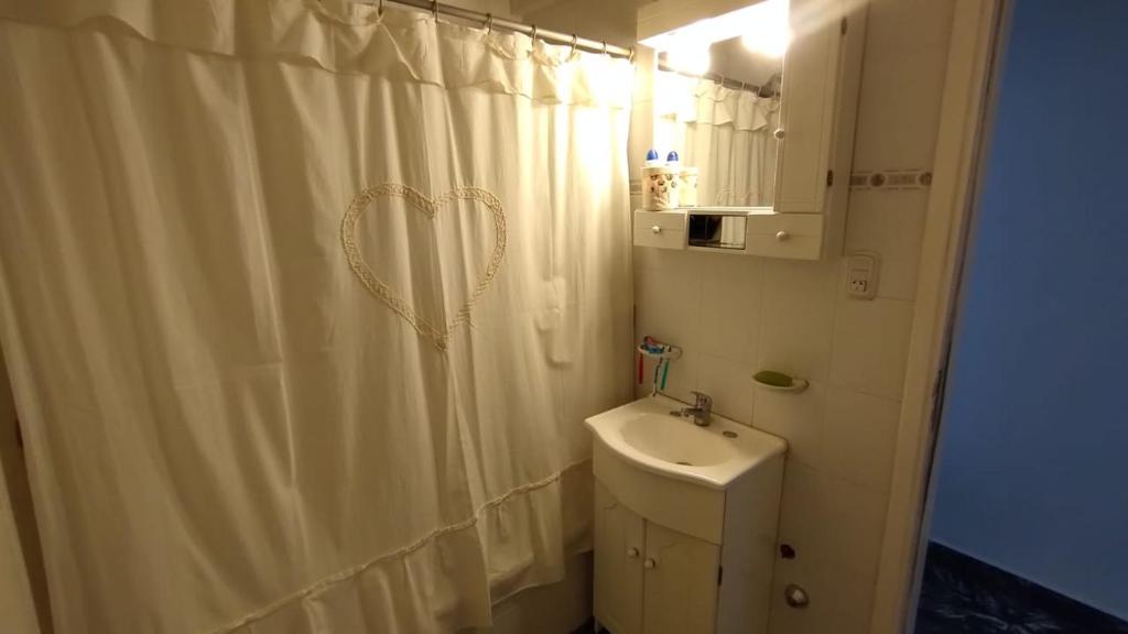 a bathroom with a white shower curtain and a sink at EMBE DEPARTAMENTO Necochea in Necochea