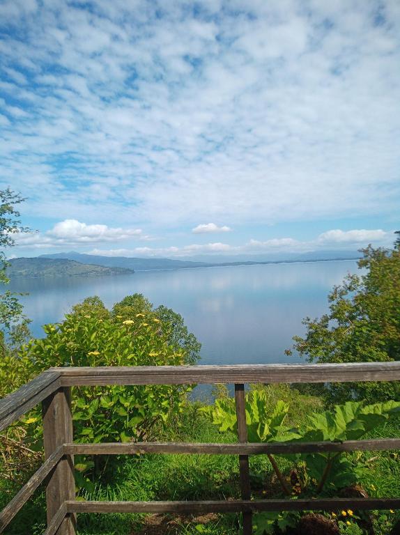 a view of a lake from a wooden fence at Cabañas Mantilhue Puyehue in Mantilhue