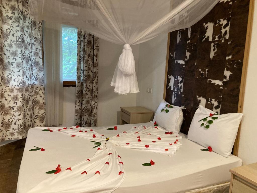 a bedroom with a white bed with red roses on it at pasha nungwi zanzibar in Nungwi