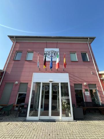 a pink building with flags in front of it at Confidence Hotel Viadana in Viadana