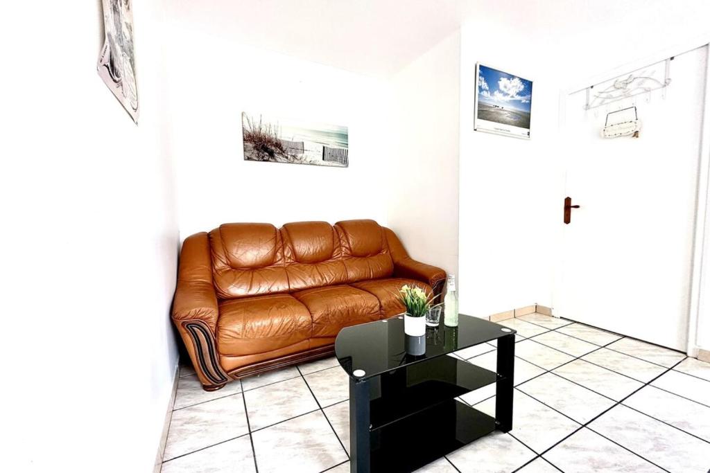 Un sofá de cuero marrón en una sala de estar con una mesa. en Le Fleuri-Plain-pied-St Valery & Le Crotoy à 10min, en Noyelles-sur-Mer