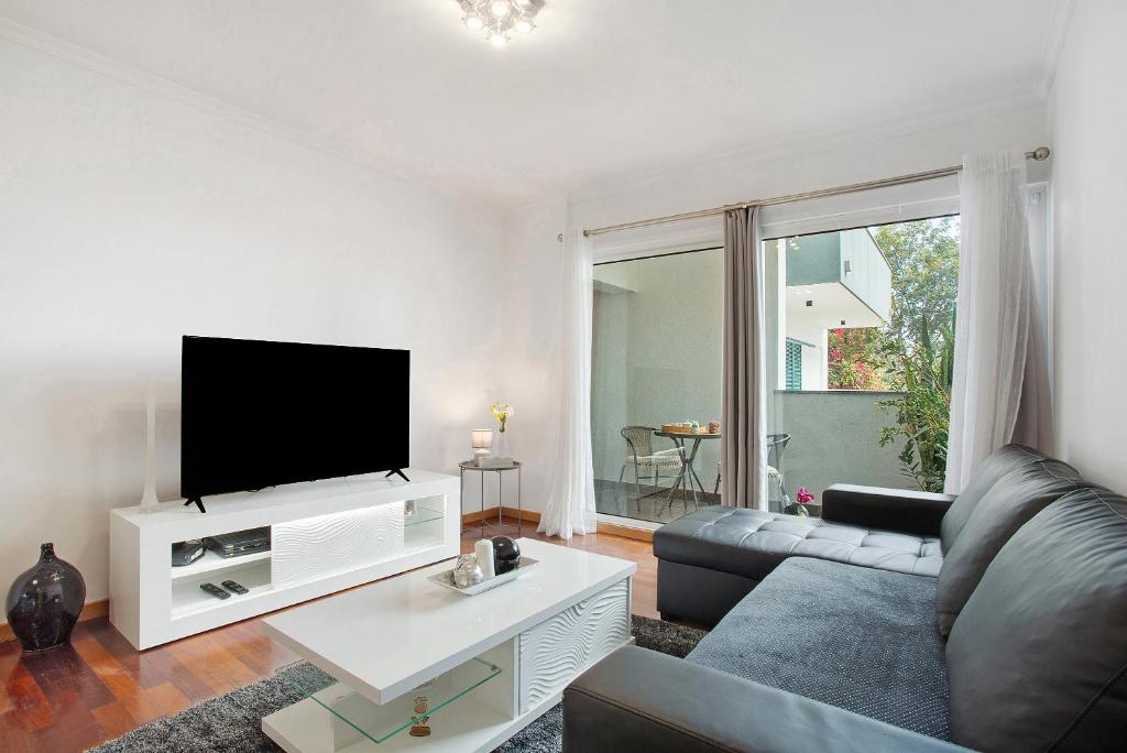 a living room with a couch and a flat screen tv at Casa Nóbrega in Caniço