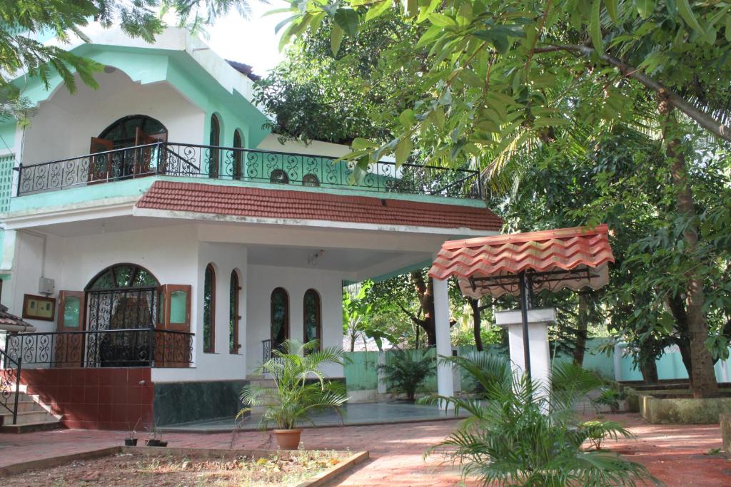 a house with a balcony and a tree at Shalom Dream Home in Candolim