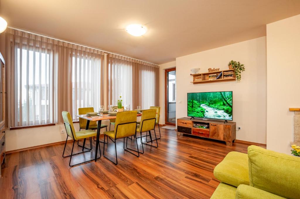 ein Wohnzimmer mit Tisch und Stühlen und einem Fernseher in der Unterkunft GREEN STAR Grand Resort Pamporovo in Pamporowo