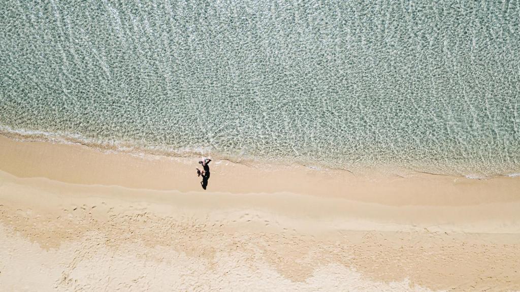 een persoon op een strand naast de oceaan bij Hotel Aquadulci in Chia