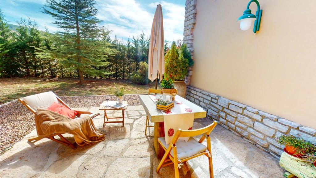 a patio with chairs and a table and an umbrella at Casa Las Tinajas in Alcalá de la Selva