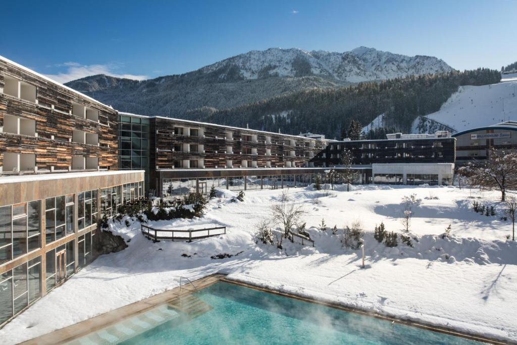 a resort with a swimming pool in the snow at Falkensteiner Hotel & Spa Carinzia Superior in Tröpolach