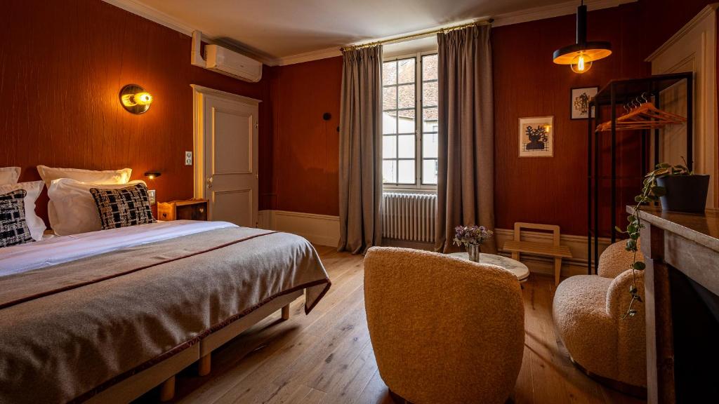 a bedroom with orange walls and a bed and two chairs at Le Prieuré d'Arbois in Arbois