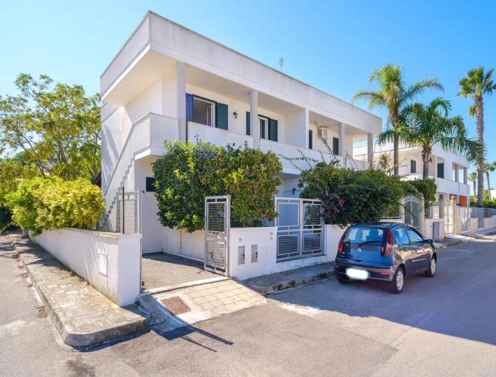 ein Auto, das vor einem weißen Gebäude parkt in der Unterkunft Coral Bay House in Torre dell'Orso