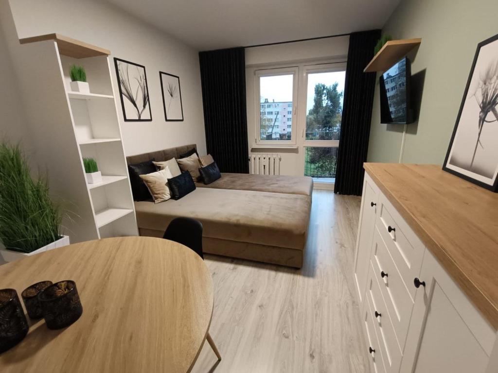 a living room with a bed and a table at Piotrków Trybunalski Comfort Apartment by BookingHost in Piotrków Trybunalski