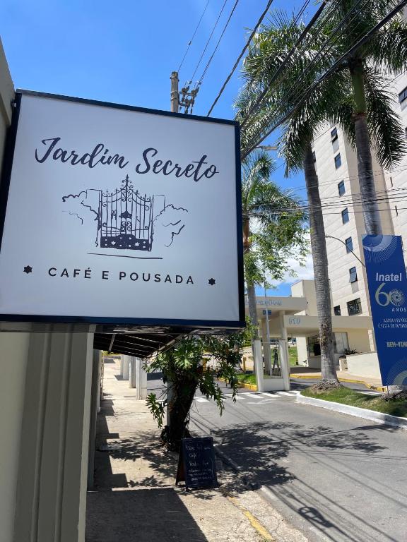 a sign for a cafe e poulada on a street at Café e Pousada Jardim Secreto in Santa Rita do Sapucaí