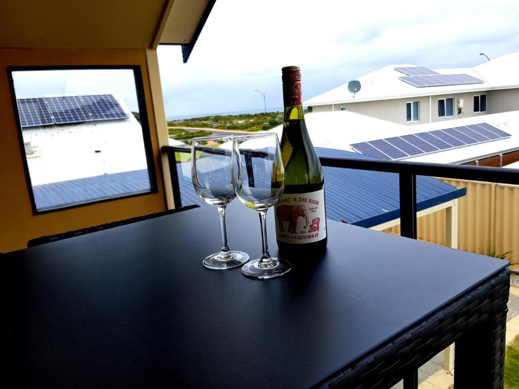 a bottle of wine and two glasses on a table at Sandy Toes and Sunsets Beach House in Bunbury