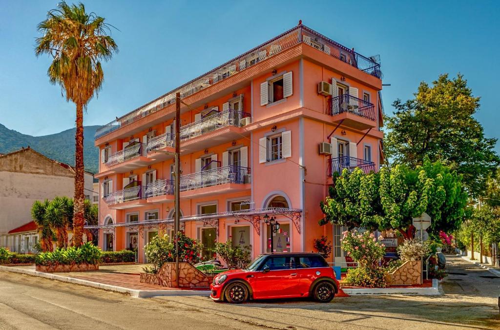 un coche rojo estacionado frente a un edificio rosa en Anemos Studios & Apartments, en Póros