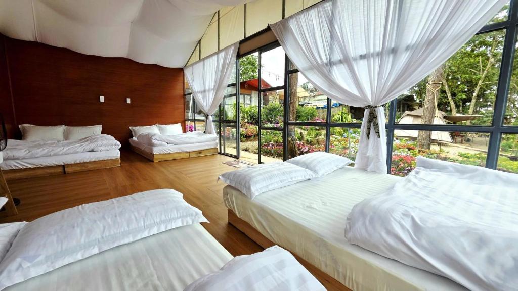 a bedroom with three beds and a large window at Hương Lúa Homestay Măng Đen in Kon Plong