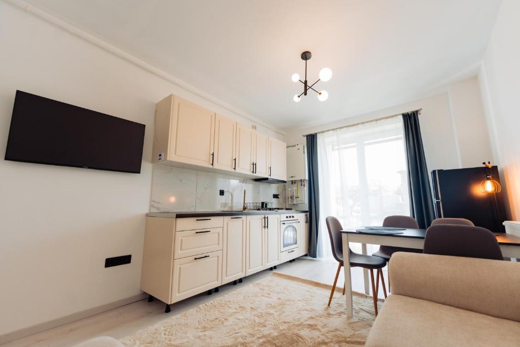 Una cocina y un comedor con mesa y sillas. en Cozy 2-Room Apartment - Free Parking - Close to Airport, en Apahida