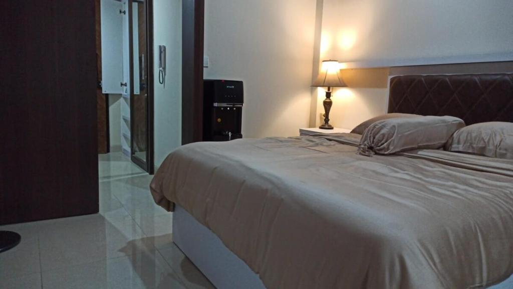 a bedroom with a large bed with a lamp on it at Ruby Apartment #29 in Yogyakarta