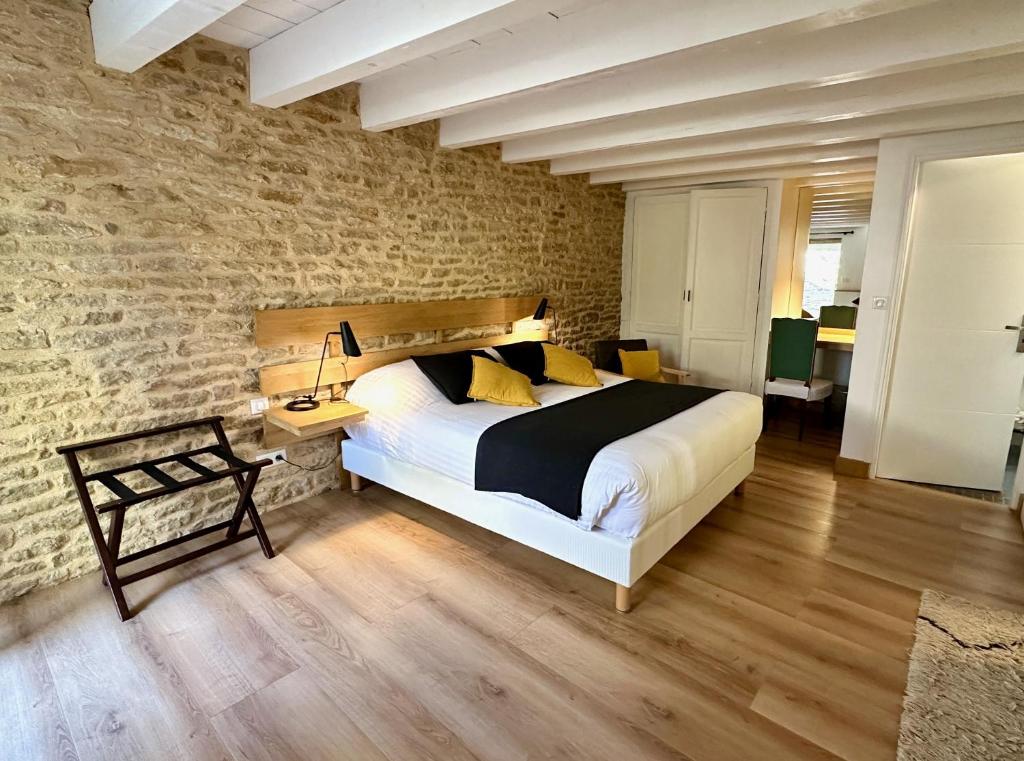 een slaapkamer met een groot bed en een bakstenen muur bij Clos de Fougères - Cocon in Montoillot