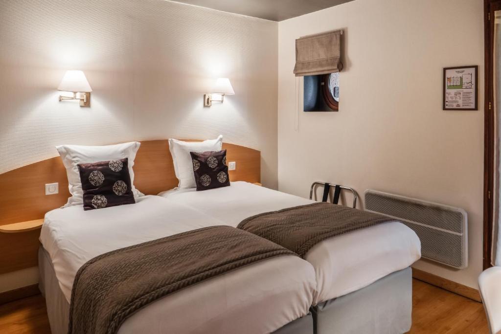 a bedroom with a large white bed with pillows at Logis Hôtel Restaurant Le Quai Fleuri in Voves