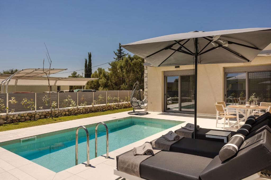 a swimming pool with an umbrella and a table at Ionian Treasure Suites in EFL