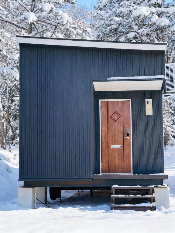 a black building with a brown door in the snow at Lagom Hakuba in Hakuba