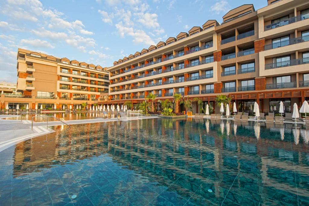 a hotel with a large swimming pool in front of a building at Aletris Deluxe Hotel & SPA in Side