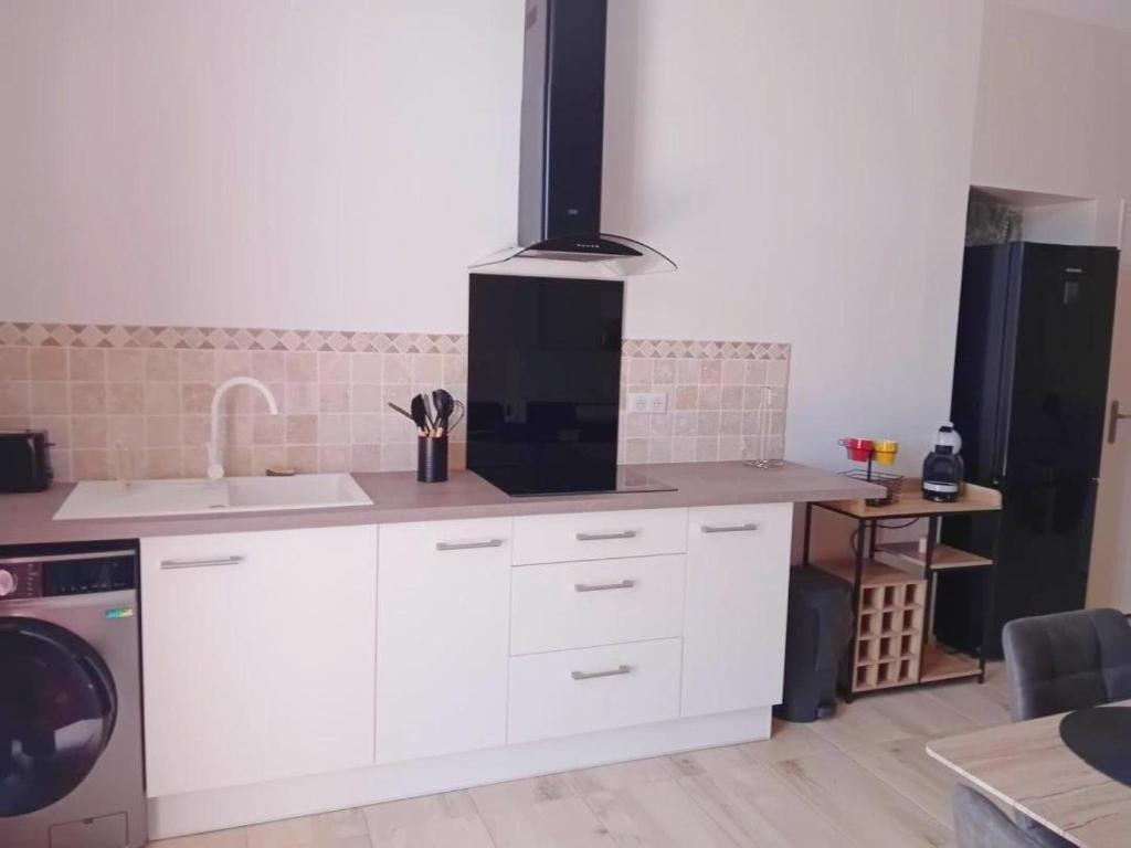a kitchen with white cabinets and a stove at Gite tafan in Pouillon