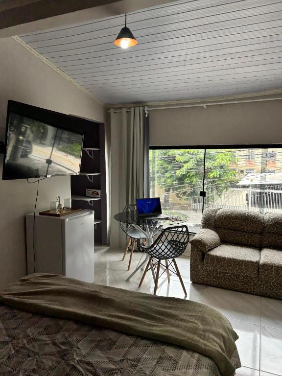a bedroom with a couch and a table and a television at A melhor localização de Belém do Pará in Belém