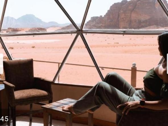two people sitting in a room with a view of the desert at Wadi Rum Luxurious Camp View in Wadi Rum
