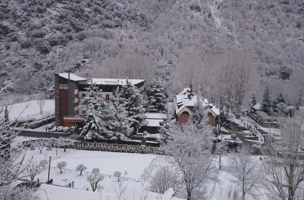 a building covered in snow in front of a mountain at Hotel SNÖ Condes del Pallars in Rialp