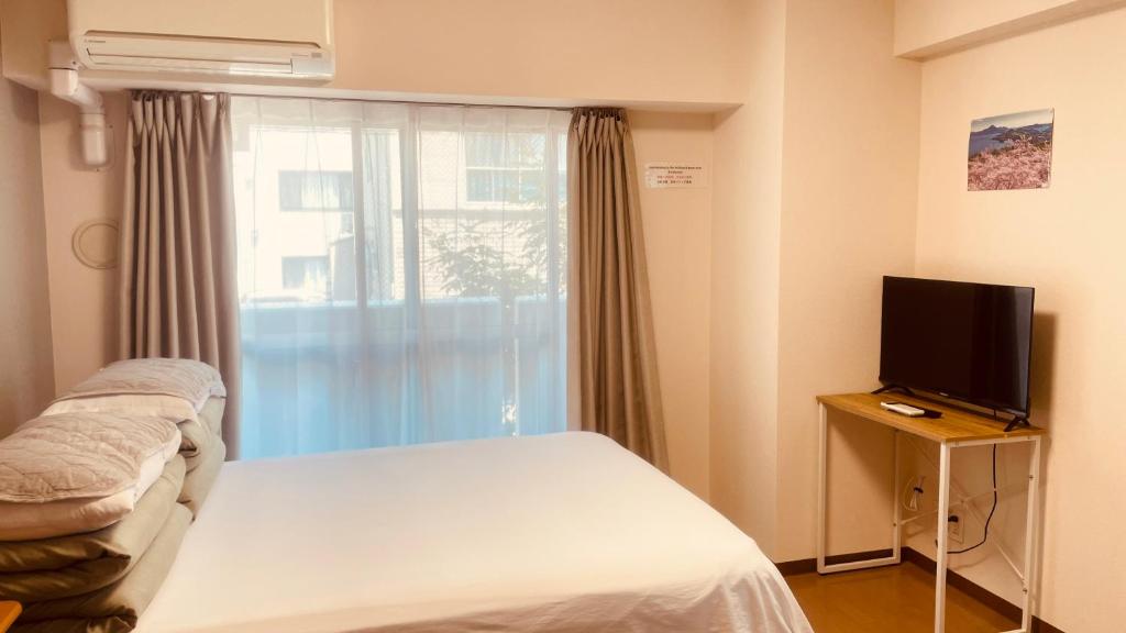 a room with a bed and a tv and a window at SkyHotel Ryogoku 駅徒歩4分 in Tokyo
