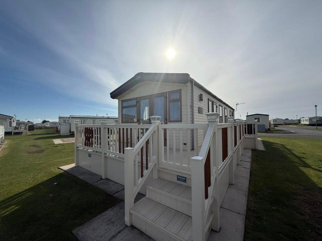 a small white house with a porch and stairs at Skegness Retreats The Grange F59 in Ingoldmells