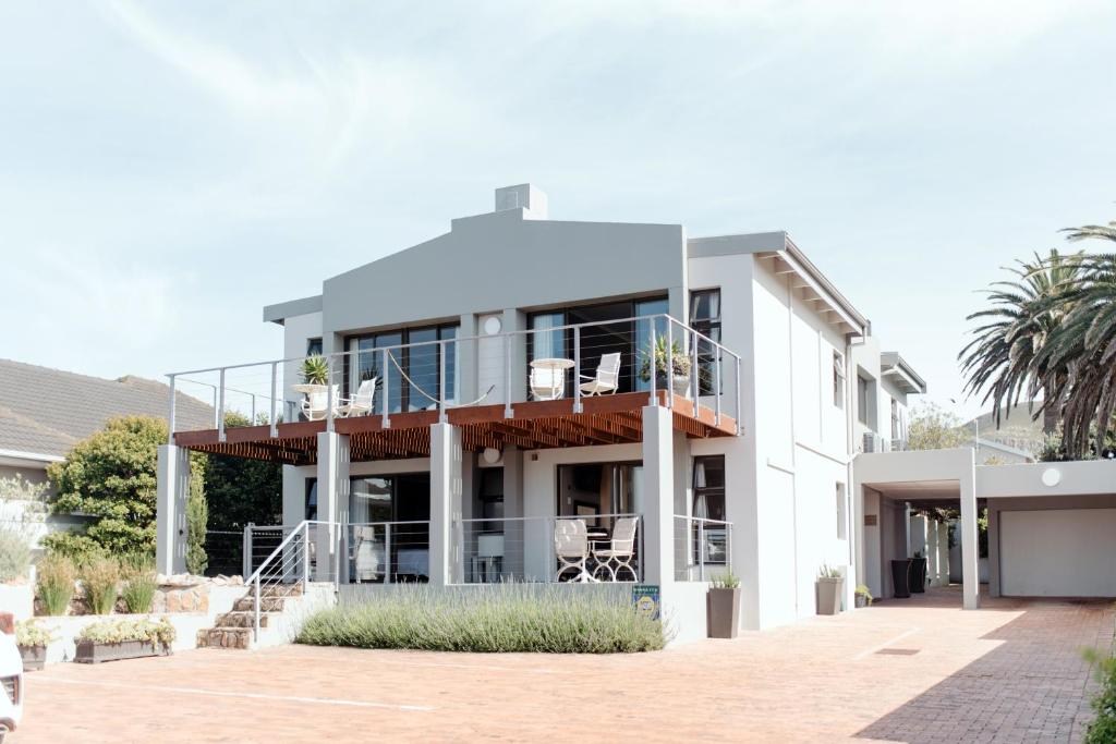 een groot wit gebouw met een balkon en terras bij Whale Away Guest House in Hermanus