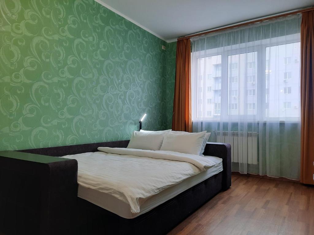 ein Schlafzimmer mit einem Bett und einer grünen Wand in der Unterkunft Двокімнатна квартира на Садовому з балконом in Shcherbani