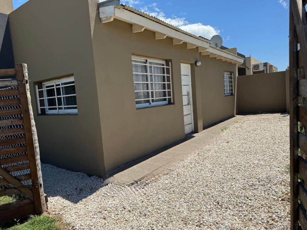 a house with a fence next to a building at Casa una habitación, 4 personas, zona parque in Necochea