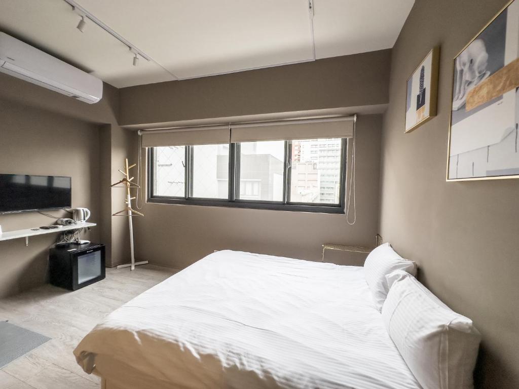 een slaapkamer met een wit bed en een raam bij meimo文旅 in Taichung