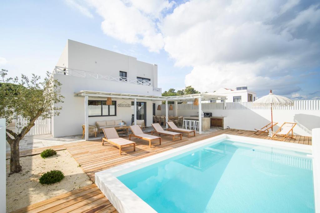 a villa with a swimming pool and a house at Carvalhal Beach House in Carvalhal
