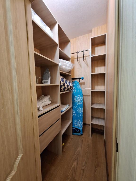 ein begehbarer Kleiderschrank mit Holzregalen und einer blauen Flasche in der Unterkunft Однокімнатна вартира на Садовому з кондиционером in Shcherbani